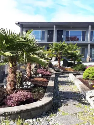 a house with palm trees in front of it at Port-O-Call Inn in Nanaimo
