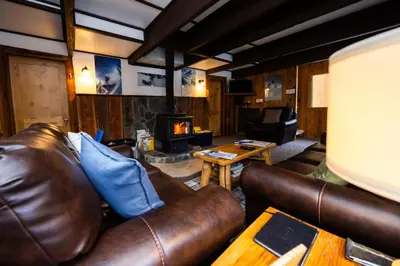 a living room with a leather couch and a fireplace at Red Shutter Inn in Rossland
