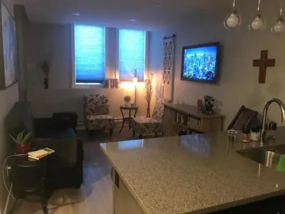 a kitchen and living room with a cross on the wall at Home Sweet Condo in Calgary