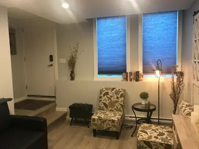 a living room with a chair and a table and two windows at Home Sweet Condo in Calgary
