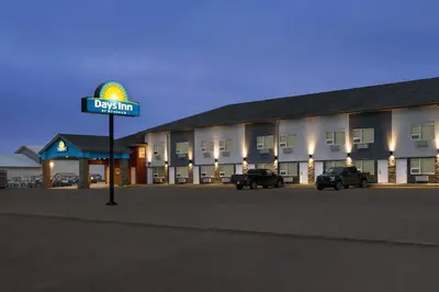 a sign for a hotel with cars parked in a parking lot at Days Inn by Wyndham Wainwright in Wainwright