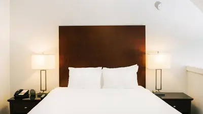 a bedroom with a bed with two lamps and a phone at Mountain Side Hotel Whistler by Executive in Whistler