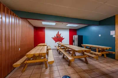 a row of wooden tables in a room with a maple leaf on the wall at The Raging Elk Adventure Lodging in Fernie