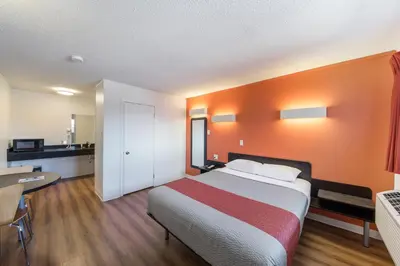 a bedroom with a large bed with an orange wall at Motel 6-Cranbrook, BC in Cranbrook