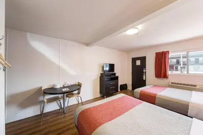 a hotel room with two beds and a desk at Motel 6-Cranbrook, BC in Cranbrook