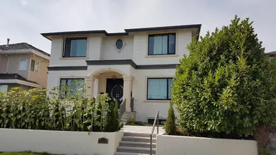 a white house with some bushes in front of it at Metropolis MetroTown Area lovely place 2 or 1 bedrooms suite in New Westminster