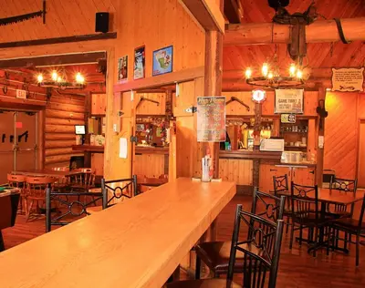 a restaurant with a long wooden table and chairs at Cariboo Lodge in Clinton
