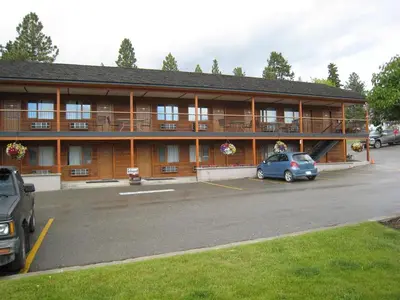 a building with a car parked in a parking lot at Cariboo Lodge in Clinton