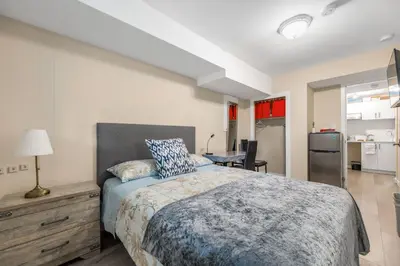 a bedroom with a bed and a desk and a kitchen at Orchid House near Vancouver YVR Airport in Richmond