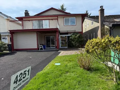 a house with a for sale sign in the front yard at Orchid House near Vancouver YVR Airport in Richmond