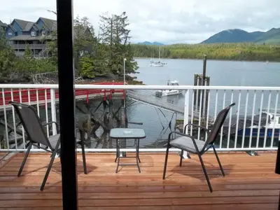 a balcony with two chairs and a table and a view of a lake at Bayshore Waterfront Inn in Ucluelet