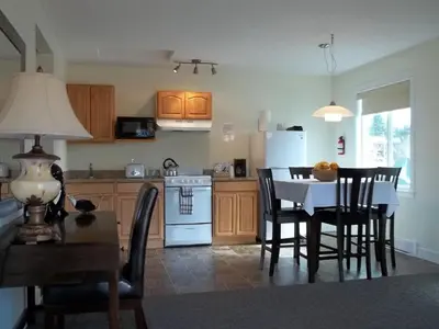 a kitchen with a table and chairs and a white refrigerator at Bayshore Waterfront Inn in Ucluelet