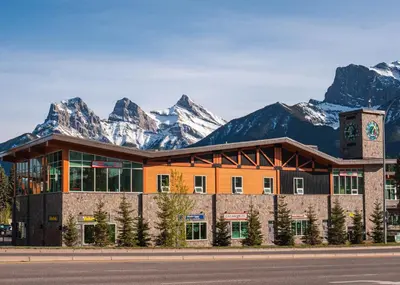 a building with snow covered mountains in the background at Canmore Downtown Hostel in Canmore
