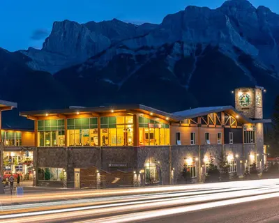 a building in front of a mountain at night at Canmore Downtown Hostel in Canmore