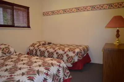 a bedroom with two beds and a lamp and a table at Seaside Villa Motel & RV Park in Powell River