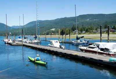a person in a kayak in the water near a dock at The Spot at Porpoise Bay in Sechelt