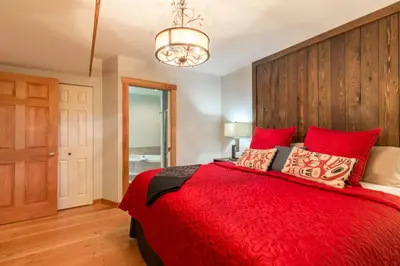 a bedroom with a red bed with a wooden headboard at Tranquility Bay Waterfront Inn in Sechelt