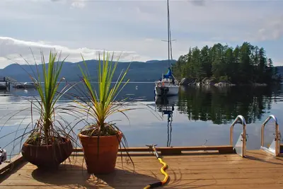two potted plants on a dock with a boat in the water at Tranquility Bay Waterfront Inn in Sechelt