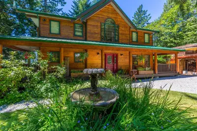 a large wooden house with a red door at Tranquility Bay Waterfront Inn in Sechelt