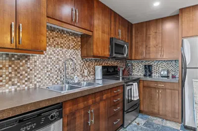 a kitchen with wooden cabinets and a sink at Heavenly Mountain Condo managed by Little Sister Getaways in Canmore