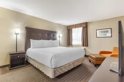 a hotel room with a large bed and a chair at Best Western Cold Lake Inn in Cold Lake