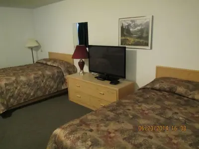 a hotel room with two beds and a flat screen tv at Lazy J Motel in Claresholm
