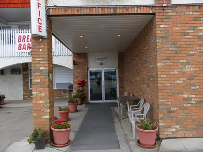 a brick building with potted plants and a bar sign at Lazy J Motel in Claresholm