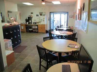 a restaurant with tables and chairs and a kitchen at Lazy J Motel in Claresholm