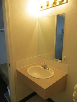 a bathroom sink with a light and a mirror at Lazy J Motel in Claresholm