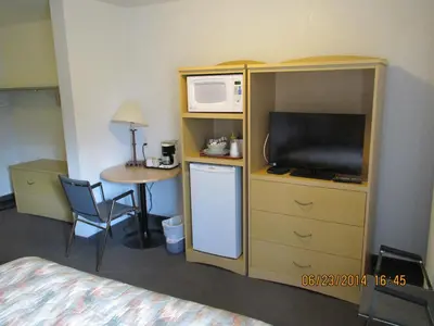 a hotel room with a bed and a microwave and a table at Lazy J Motel in Claresholm