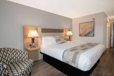a hotel room with a large bed and a chair at Coast Abbotsford Hotel & Suites in Abbotsford