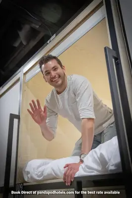 a man sitting on a bed in a bus at Panda Pod Hotel in Richmond