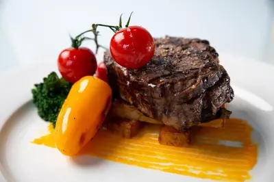a plate of food with a steak and tomatoes at Holiday Inn Edmonton South - Evario Events by IHG in Edmonton