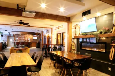 a restaurant with wooden tables and chairs and a flat screen tv at Western Lodge in Kimberley