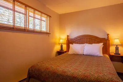 a bedroom with a bed with white pillows and a window at Fairmont Hot Springs Resort in Fairmont Hot Springs