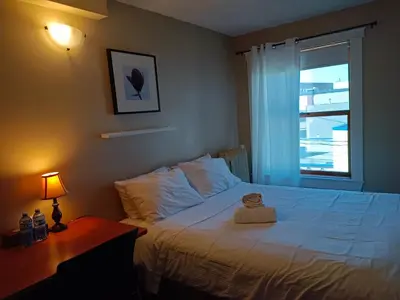 a bedroom with a bed and a lamp and a window at Painted Turtle Guesthouse in Nanaimo