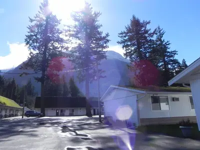 a house in a driveway with a mountain in the background at Skagit Motel in Hope