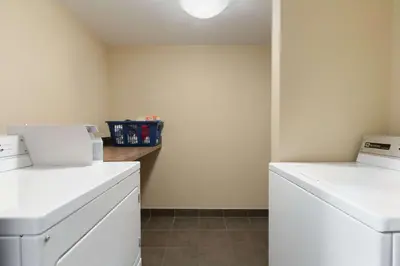 a laundry room with two white washers and a counter at Days Inn by Wyndham Calgary Northwest in Calgary