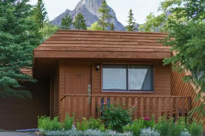 a small cabin with a fence and a mountain at The Crossing in Saskatchewan River Crossing
