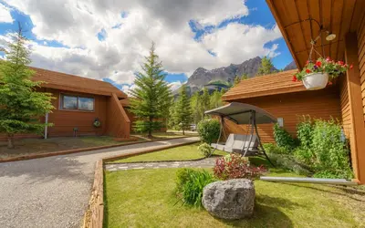 a house with a porch with a bench on the grass at The Crossing in Saskatchewan River Crossing
