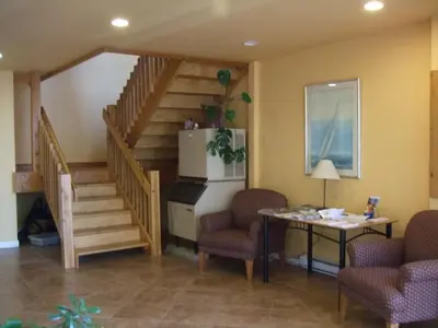 a lobby with a staircase with two chairs and a table at Island View Lodge in Powell River