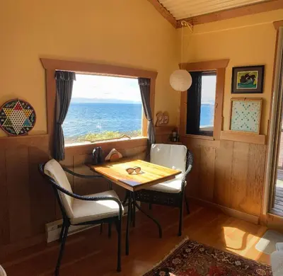 a dining room with a table and chairs and a window at Blitz Beach House Oceanside Suite in Powell River