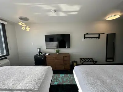 a bedroom with two beds and a flat screen tv at Waterways, A Boutique Hotel in Powell River