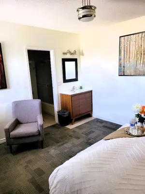 a bedroom with a bed and a chair and a sink at Royal Duke Hotel in Okotoks