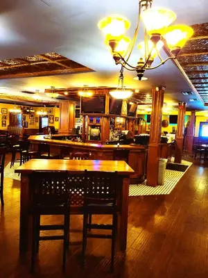 a restaurant with a bar with tables and chairs at Royal Duke Hotel in Okotoks