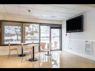 a room with a table and chairs and a flat screen tv at Riverside Motel Cache Creek in Cache Creek