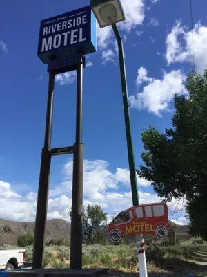a motel sign and a street light with a car in the background at Riverside Motel Cache Creek in Cache Creek