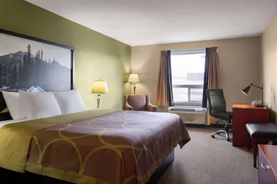 a hotel room with a bed and a desk and a window at Super 8 by Wyndham Sherwood Park/Edmonton Area in Sherwood Park