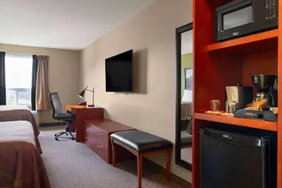 a hotel room with a bed and a desk with a computer at Super 8 by Wyndham Sherwood Park/Edmonton Area in Sherwood Park