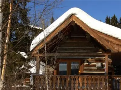 a log cabin with snow on top of it at Nakiska Bear Ranch in Clearwater